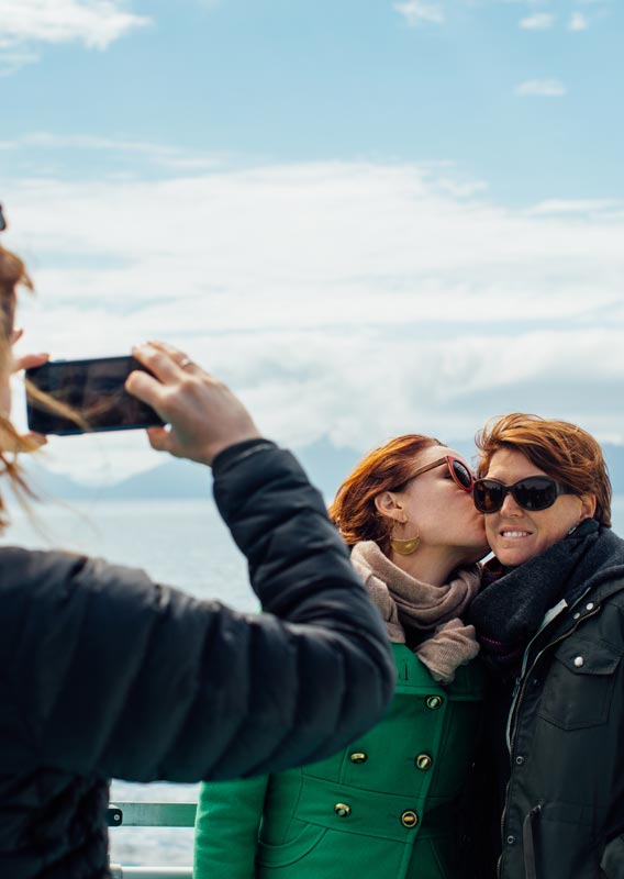 Mother and daughter pose on Kenai Fjords Tour boat while someone takes a photo of them