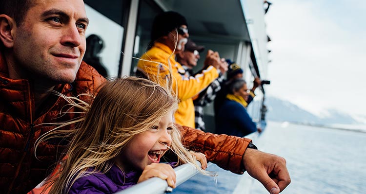 A dad and kid at the viewing deck on a boat cruise.