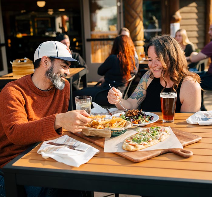 Two people sit for lunch at a patio dining table.