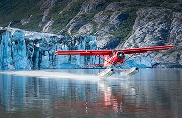 A floatplane landed on the sea near a large tidewater glacier.