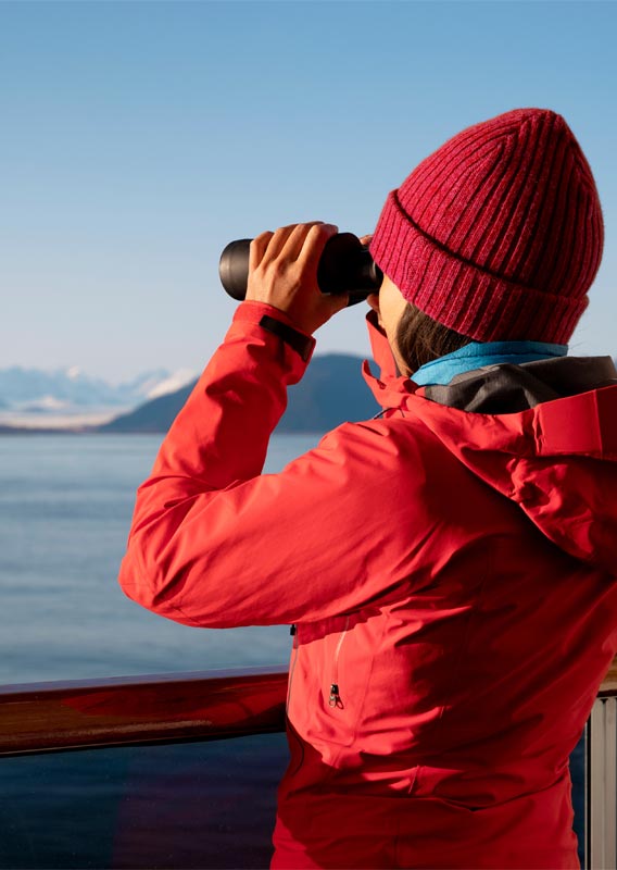 Person holding binoculars looking at the mountains