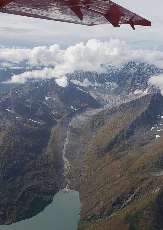 An aerial view from a small plane looking down at a wide valley and mountains.