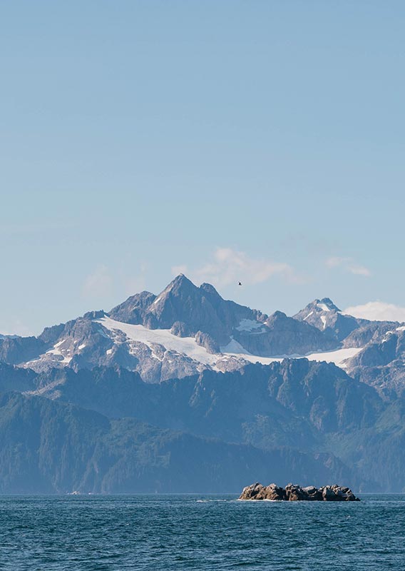 A view across the sea towards tall mountains with a high glacier.