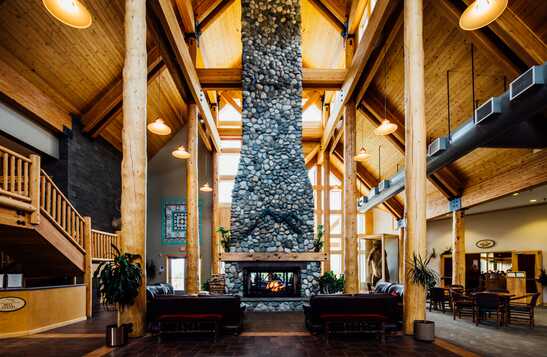 A floor-to-ceiling stone fireplace in a large wooden lodge.