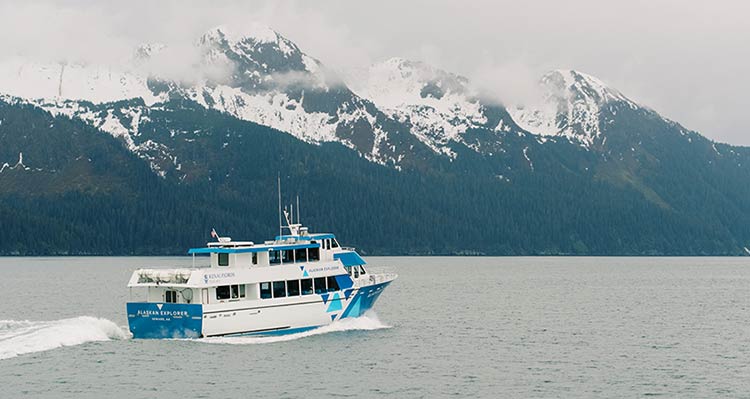 The Alaskan Explorer Boat with snow-covered mountains in the background