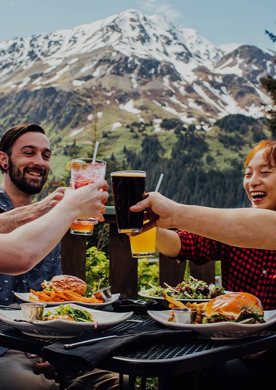 A group of people raise their glasses in a cheers on a restaurant patio.