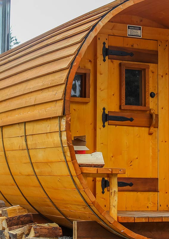 A large wooden sauna in the shape of a cylinder outdoors at Denali Cabins.