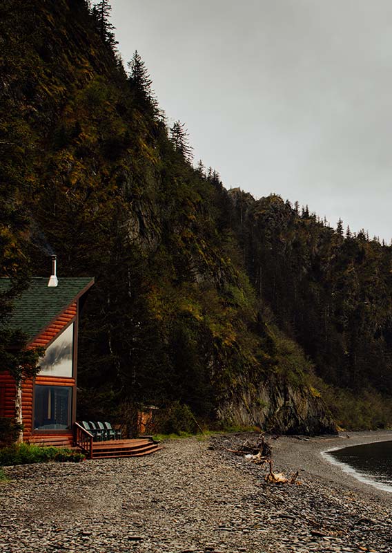 A wooden lodge at the edge of a rocky beach.