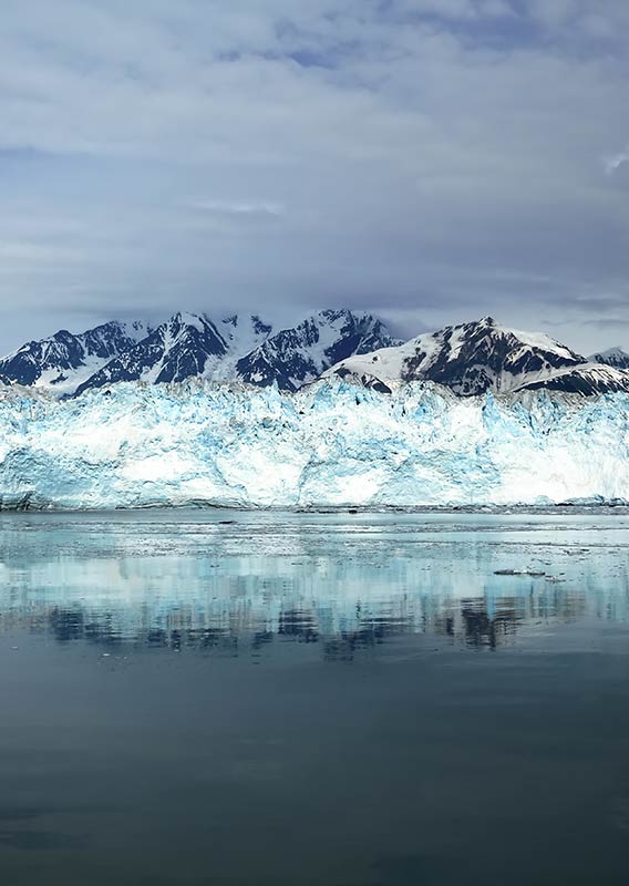 A glacier on grey ocean and grey skies.